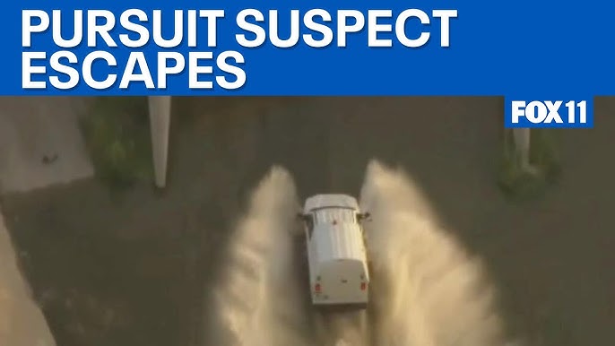 An LAPD helicopter flies above a concrete channel of the Los Angeles River as officers respond to a vehicle pursuit involving a suspect who fled into storm drains beneath the 6th Street Bridge.