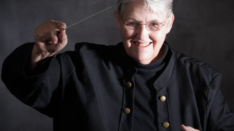 Sylvia Lee Mann conducting an orchestra, symbolizing her role as Music Director and community leader.