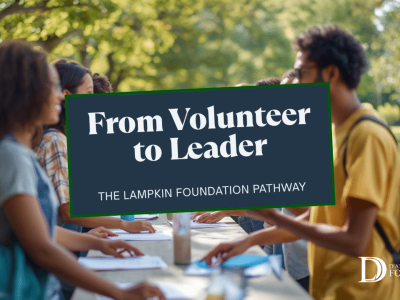 Diverse Lampkin Foundation volunteers coordinate a check-in table at a park event, greeting families and organizing badges.