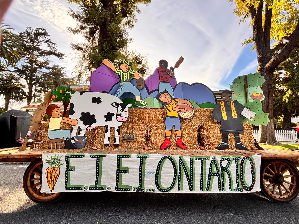E-I-E-I-Ontario agricultural heritage float featuring children, farming scenes, hay bales, and a historic wooden farm trailer during the 2026 City of Ontario Independence Day Parade.